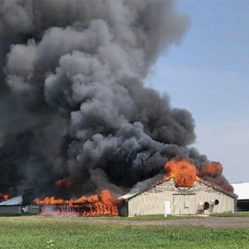 A barn on fire with black billowing smoke