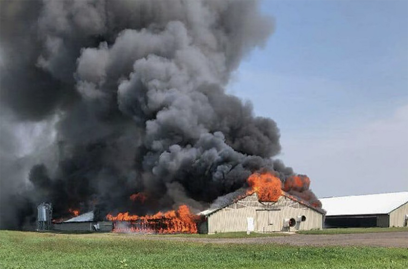 A barn on fire with black billowing smoke