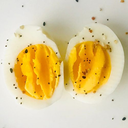 A hard boiled egg cut in half, face-up with pepper on top