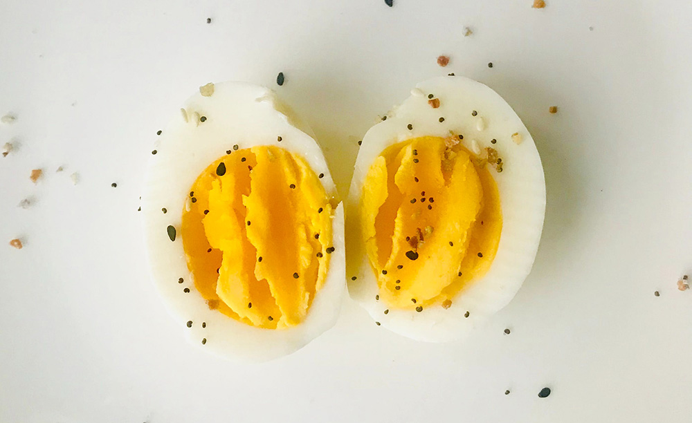 A hard boiled egg cut in half, face-up with pepper on top