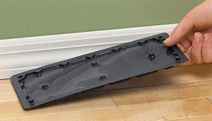 A rat trap glue board being set onto the floor